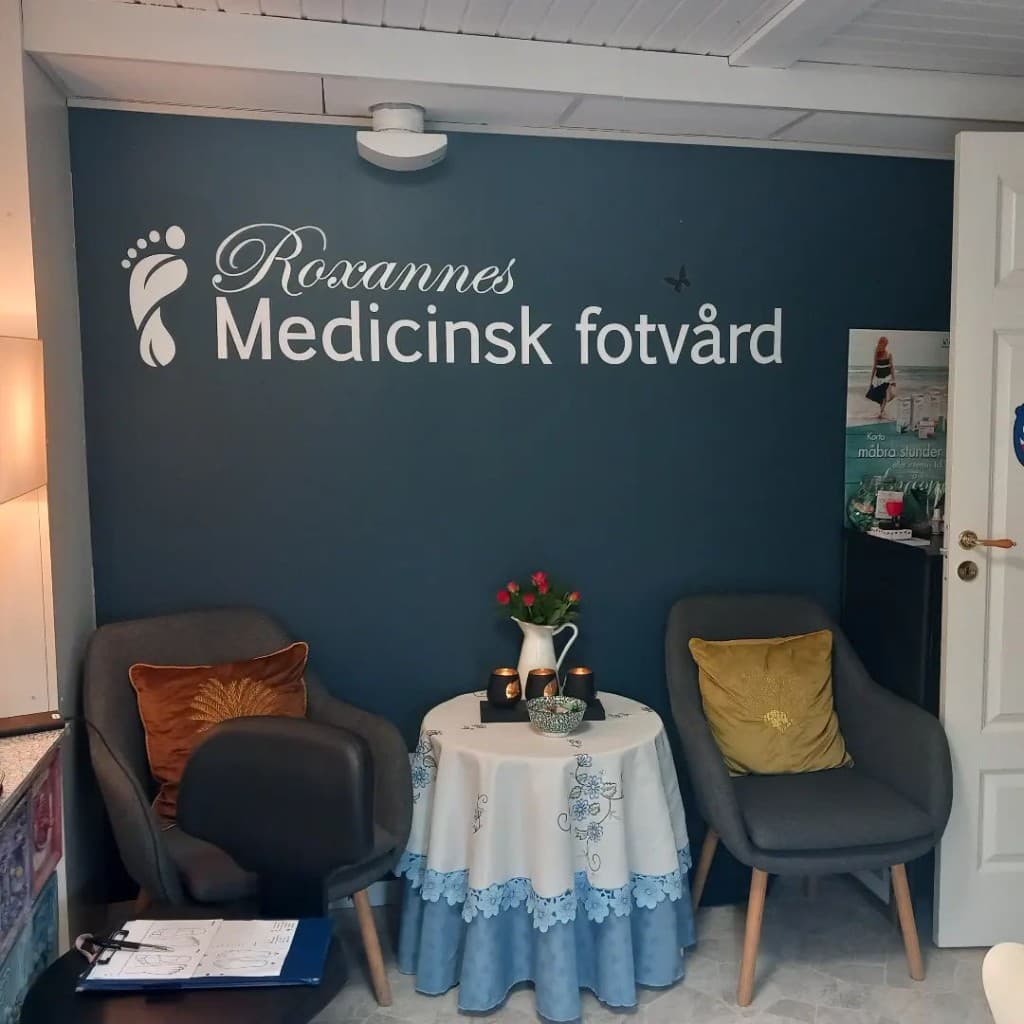 Väntrum hos Roxannes Medicinsk Fotvård & Kroppsvård med vägglogotyp och inbjudande sittplatser.